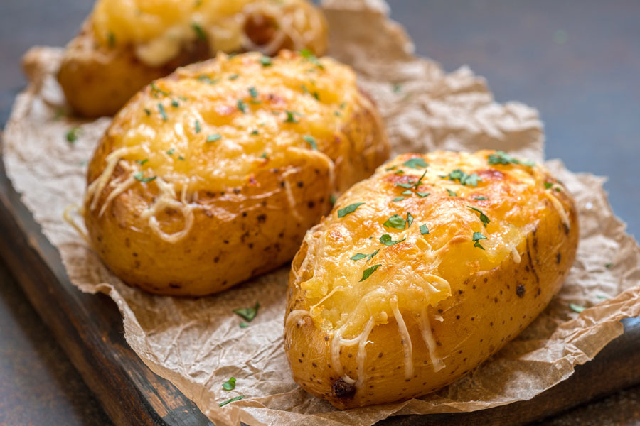 Crispy jacket potatoes on board with melted cheese